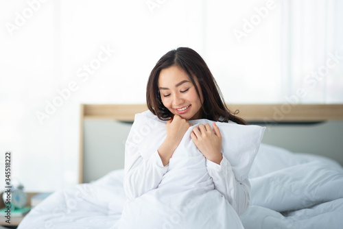 Asian woman hug the pillow in the bed smile and happy
