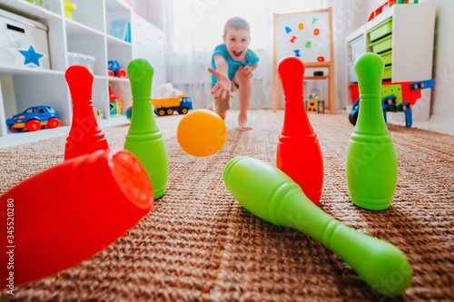 Obraz na plátně children a boy throws ball into a home bowling alley and smashes the bowling pin