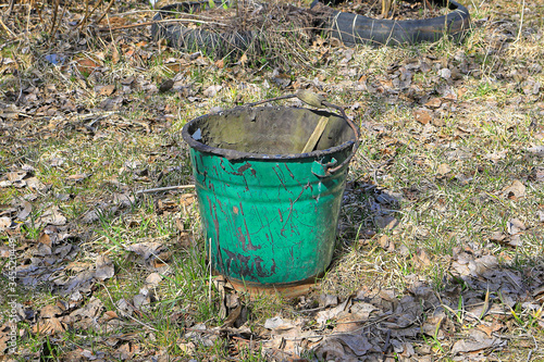 Old metal bucket in the garden on the grass among the fallen leaves