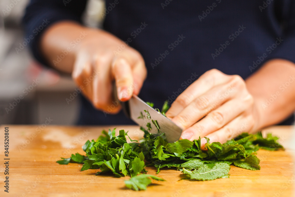 Woman cutting fresh organic parsley and mint on chopping board, making healthy low calories salad. Woman cutting fresh organic parsley and mint on chopping board, making healthy low calories salad.