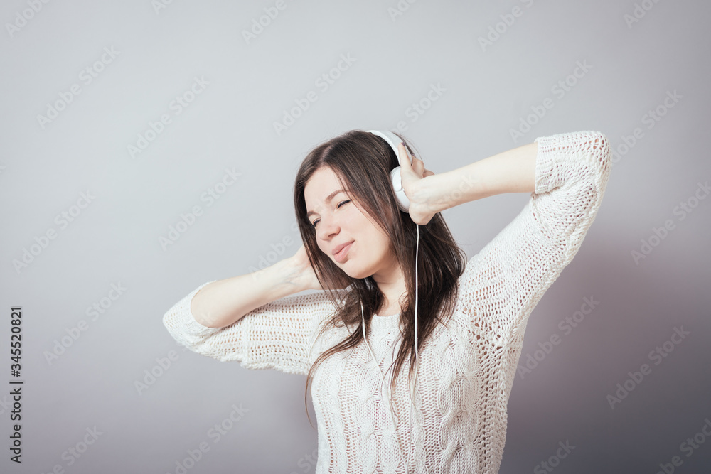 Fototapeta premium Young woman with headphones listening music .Music teenager girl dancing against isolated white background