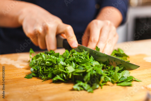 Woman cutting fresh organic parsley and mint on chopping board, making healthy low calories salad.
