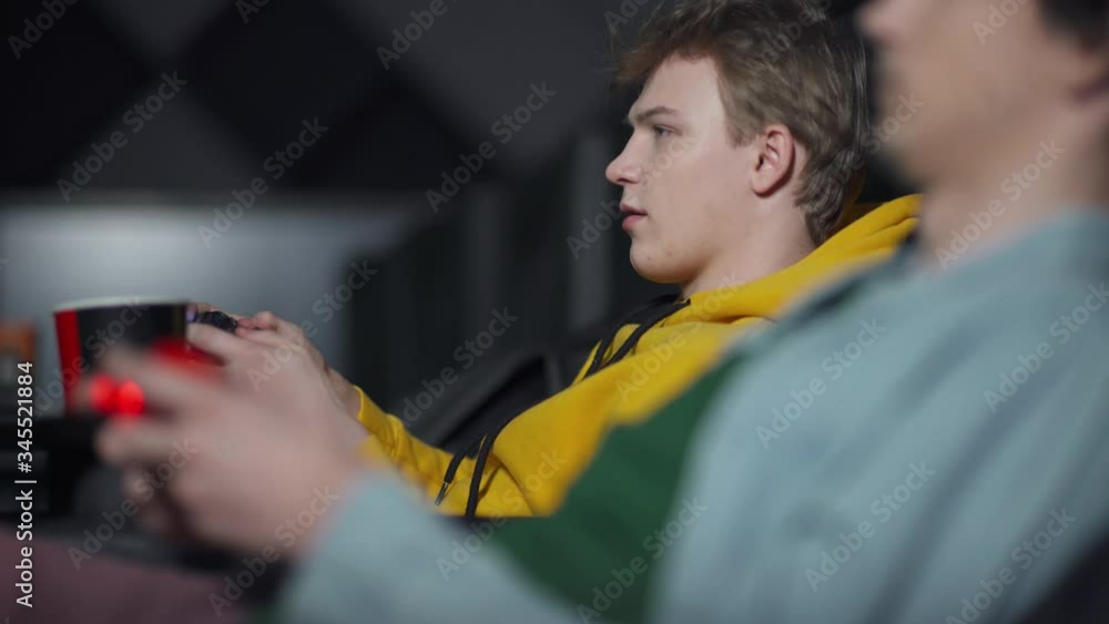 Young gamers in a movie theater, two friends playing video games on a game console, playing games on a big screen. Young gamers in a movie theater, two friends playing video games on a game console, playing games on a big screen.