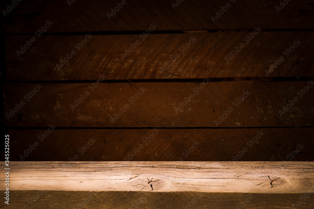 Old table top with brown concrete block wall in dark room background. Old table top with brown concrete block wall in dark room background.