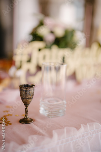 Close-up of a wedding dinner table. Metal church copper glass and glass against the background of floral composition
