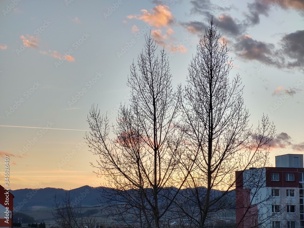Obraz premium Sunrise and sunset, beautiful clouds over the meadow, hills and buildings in the town. Slovakia