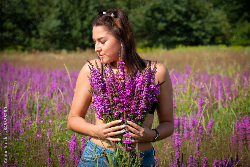 Girl enjoying in the meadow holds a bouquet of purple sage flowers in the meadow on a summer sunny day Girl enjoying in the meadow holds a bouquet of purple sage flowers in the meadow on a summer sunny day