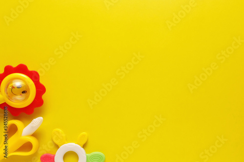 Colorful and various plastic toys for babies on a yellow background. Layout. Empty space for the text. Minimalism