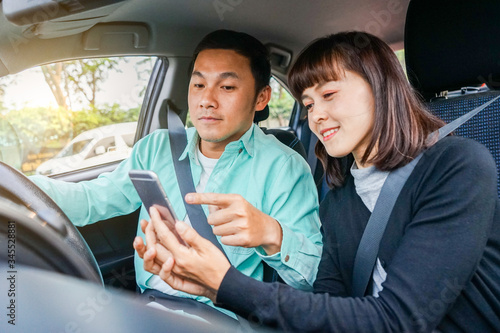 Couple asian man and woman sitting in car and looking at smartphone. Travel concept. socail concept © Patcharanan