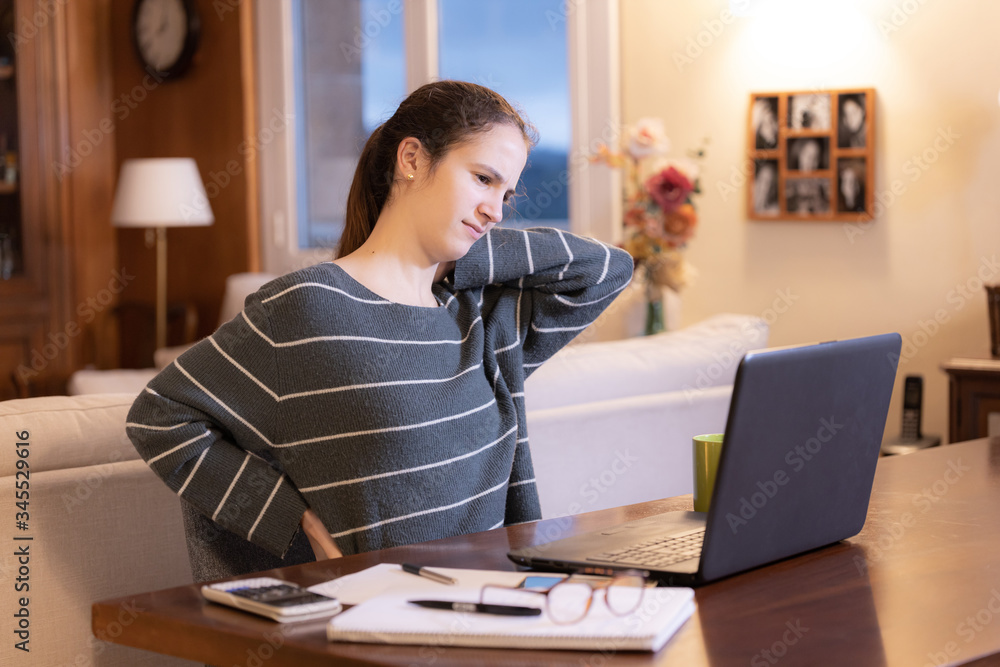 Teen girl studying remotely at home with symptoms of back pain Teen girl studying remotely at home with symptoms of back pain