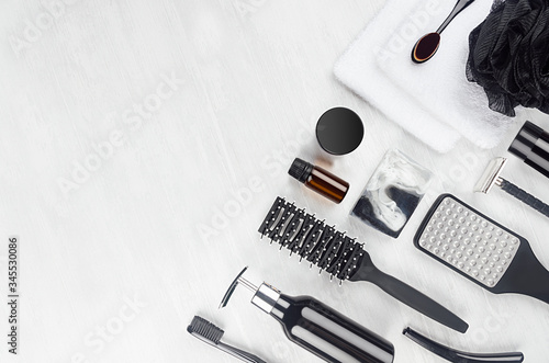 Fashion black toiletry and cosmetic products for body and skin care flat lay on white wood background, border, copy space.