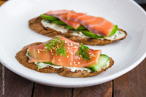 homemade sandwiches with salmon avocado cucumber cream cheese dill on white plate