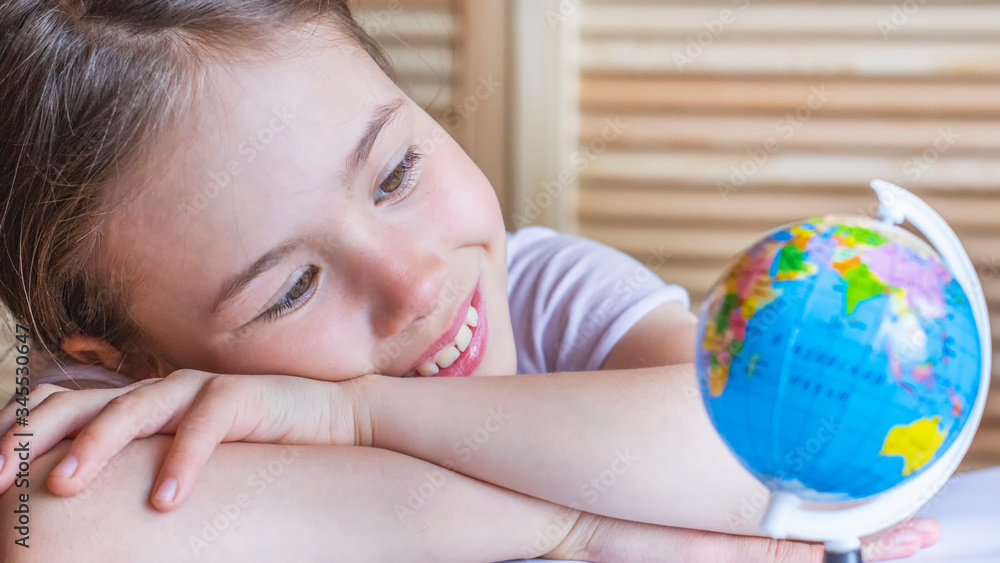 Child girl is smiling and looking at the globe, dreaming about traveling around the world. Child girl is smiling and looking at the globe, dreaming about traveling around the world.
