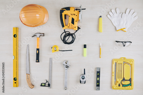 Set of construction tools on wooden table including spirit level, hammer, electric jigsaw and spanner wrench photo