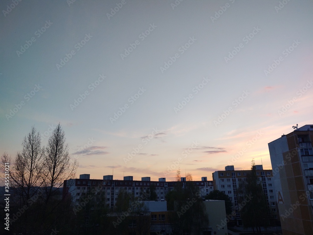 Naklejka premium Sunrise and sunset, beautiful clouds over the meadow, hills and buildings in the town. Slovakia
