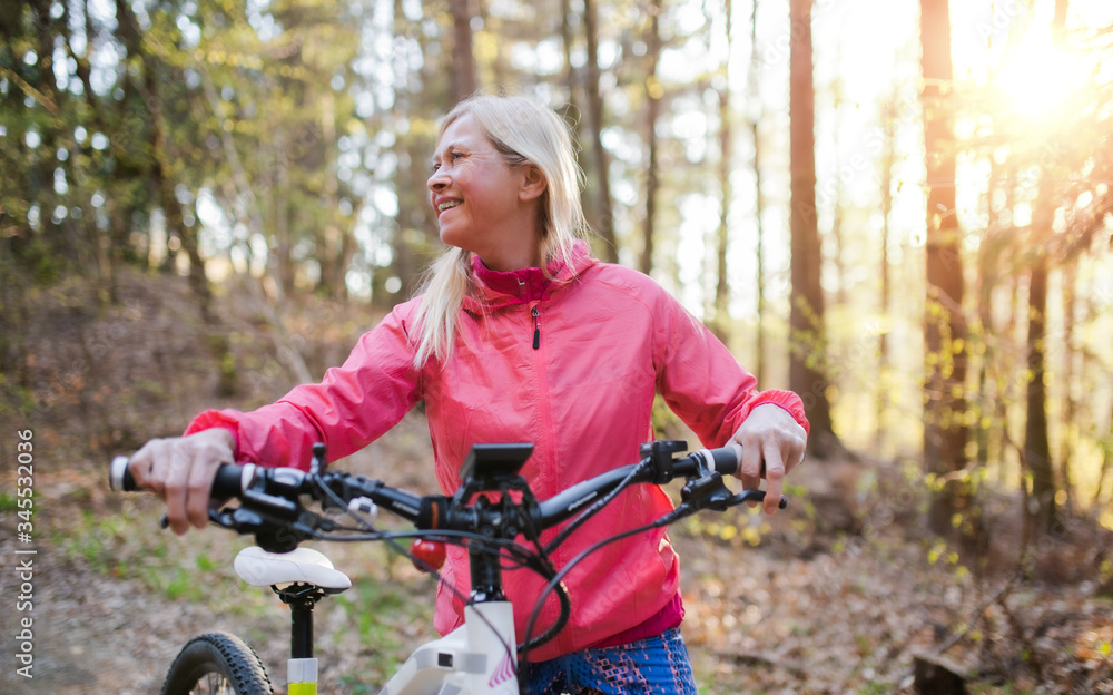 Active senior woman with e-bike cycling outdoors in nature. Active senior woman with e-bike cycling outdoors in nature.