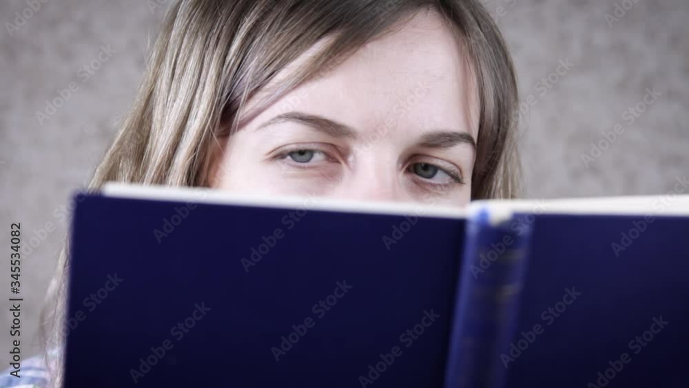 Womans eyes looking in the book, careful readings. Young woman reading book while sitting in comfortable chair Womans eyes looking in the book, careful readings. Young woman reading book while sitting in comfortable chair