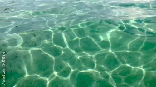 Slow motion of crystal clear translucent and transparent sea water surface with white sand  floor and ripples photo