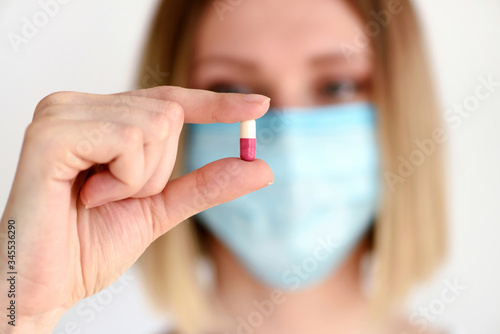 Young attractive woman holding a pill to be taken to her patient. Healthcare and medical concept.