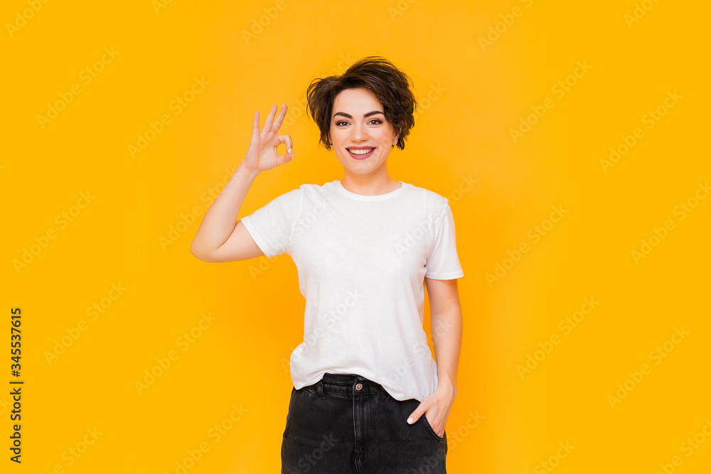 Young happy brunette woman with a short haircut in a white T-shirt on a yellow background. portrait of a young woman with various emotions on a yellow background. space for text Young happy brunette woman with a short haircut in a white T-shirt on a yellow background. portrait of a young woman with various emotions on a yellow background. space for text