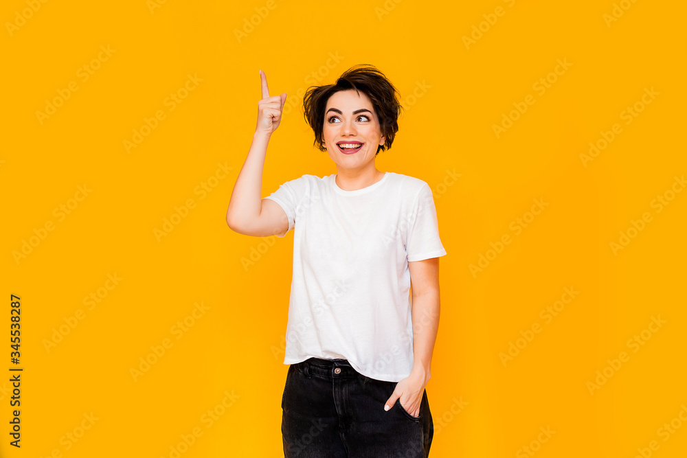 Young happy brunette woman with a short haircut in a white T-shirt on a yellow background. portrait of a young woman with various emotions on a yellow background. space for text Young happy brunette woman with a short haircut in a white T-shirt on a yellow background. portrait of a young woman with various emotions on a yellow background. space for text