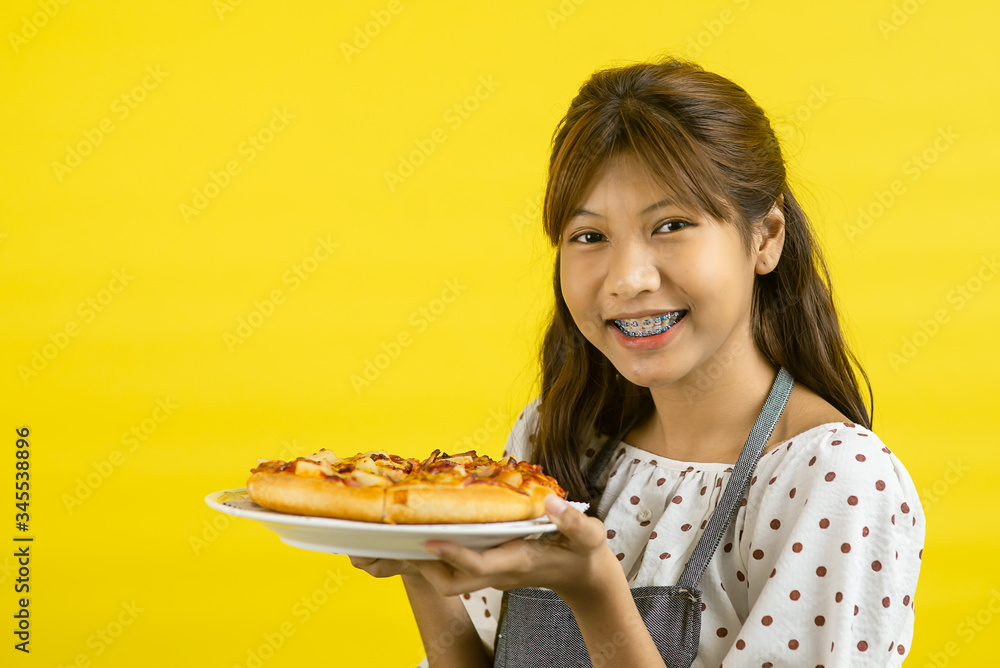 Asian teenager wearing girl holding pizza on yellow background. Asian teenager wearing girl holding pizza on yellow background.