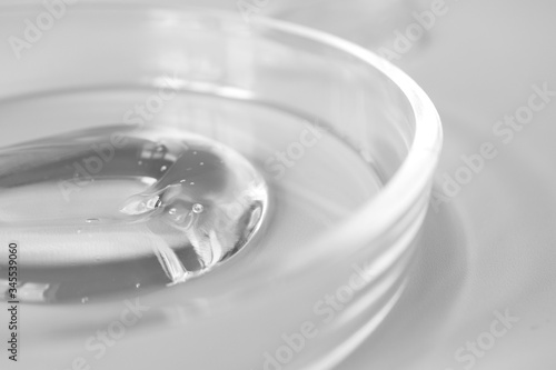 Close-up transparent aloe gel in glass petri dish smudge on white background. Concept laboratory tests and research, making cosmetic. Purity facial cleanser, peeling, shampoo or shower gel