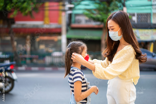 Chinese mother helping her daughter wearing pm 2.5 mask for protective Covid 19 or Corona virus in Covid 19 outbreak situation. Virus outbreak, Medical, Healthy, Healthcare, Covid 19 or Corona concept