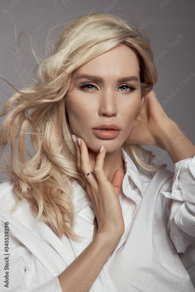 Blonde woman with hair flying in the wind, a close-up portrait of a girl in a white shirt, natural makeup and clean delicate skin Blonde woman with hair flying in the wind, a close-up portrait of a girl in a white shirt, natural makeup and clean delicate skin