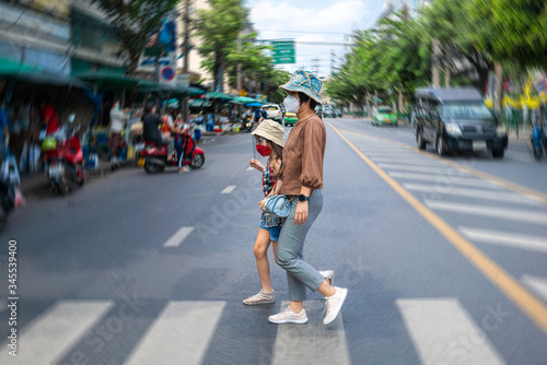 Asian mother wearing n95 face mask walking across the street with her beautiful daughter during corona virus outbreak and city lock down policy. social distancing or new normal concepts © tuastockphoto