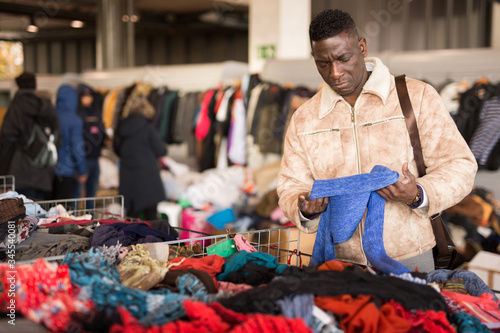 Afro-American guy considers sacond hands clothes on flea market