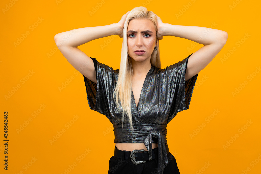 portrait of a blonde attractive displeased young woman on yellow studio background portrait of a blonde attractive displeased young woman on yellow studio background