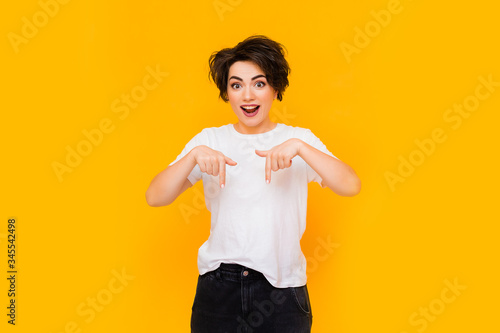 Young happy brunette woman with a short haircut in a white T-shirt on a yellow background. portrait of a young woman with various emotions on a yellow background. space for text
