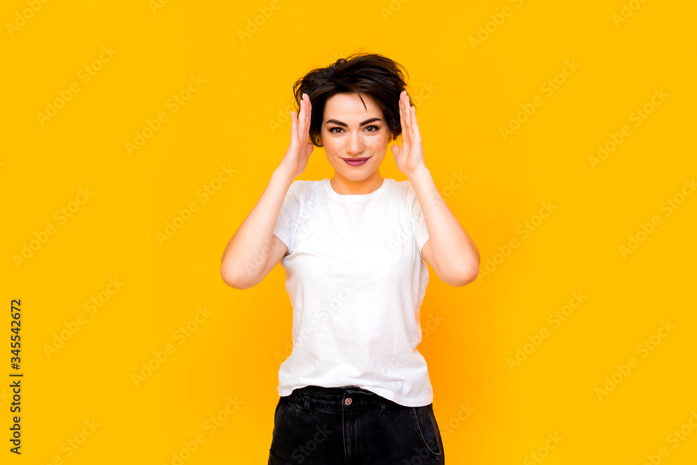 Young happy brunette woman with a short haircut in a white T-shirt on a yellow background. portrait of a young woman with various emotions on a yellow background. space for text Young happy brunette woman with a short haircut in a white T-shirt on a yellow background. portrait of a young woman with various emotions on a yellow background. space for text