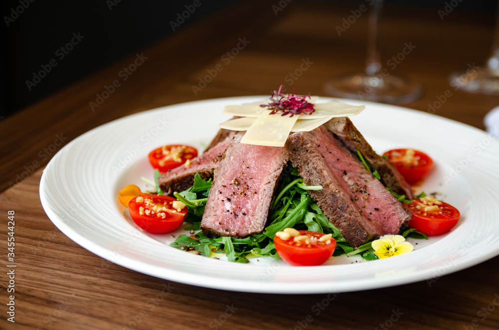 Cooked pork meat on top of rocket salad with cherry tomatoes Cooked pork meat on top of rocket salad with cherry tomatoes