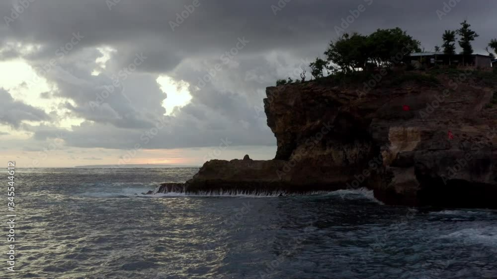 Dramatic sunset at Nusa Penida island with volcanic rock coastline near Broken beach, Aerial flyover shot Dramatic sunset at Nusa Penida island with volcanic rock coastline near Broken beach, Aerial flyover shot