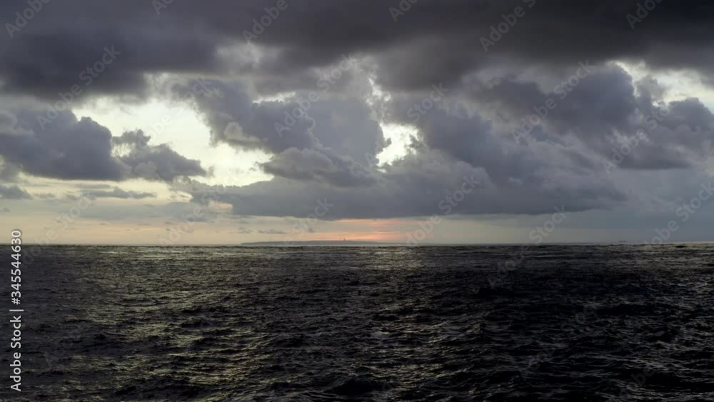 Dramatic cloudy sunset at Nusa Penida island with the island of Bali Indonesia in the distance, Aerial pedestal down shot Dramatic cloudy sunset at Nusa Penida island with the island of Bali Indonesia in the distance, Aerial pedestal down shot