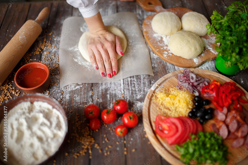 Fototapeta premium woman kneads the dough with hands while cooking pizza