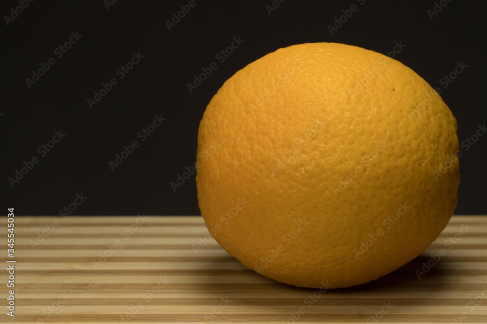 Three fresh orange on circle wood tray with dark background Three fresh orange on circle wood tray with dark background