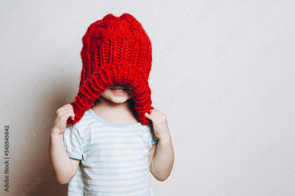 portrait of a little girl of 2 years wearing a red hat and being photographed showing different emotions against a light wall portrait of a little girl of 2 years wearing a red hat and being photographed showing different emotions against a light wall