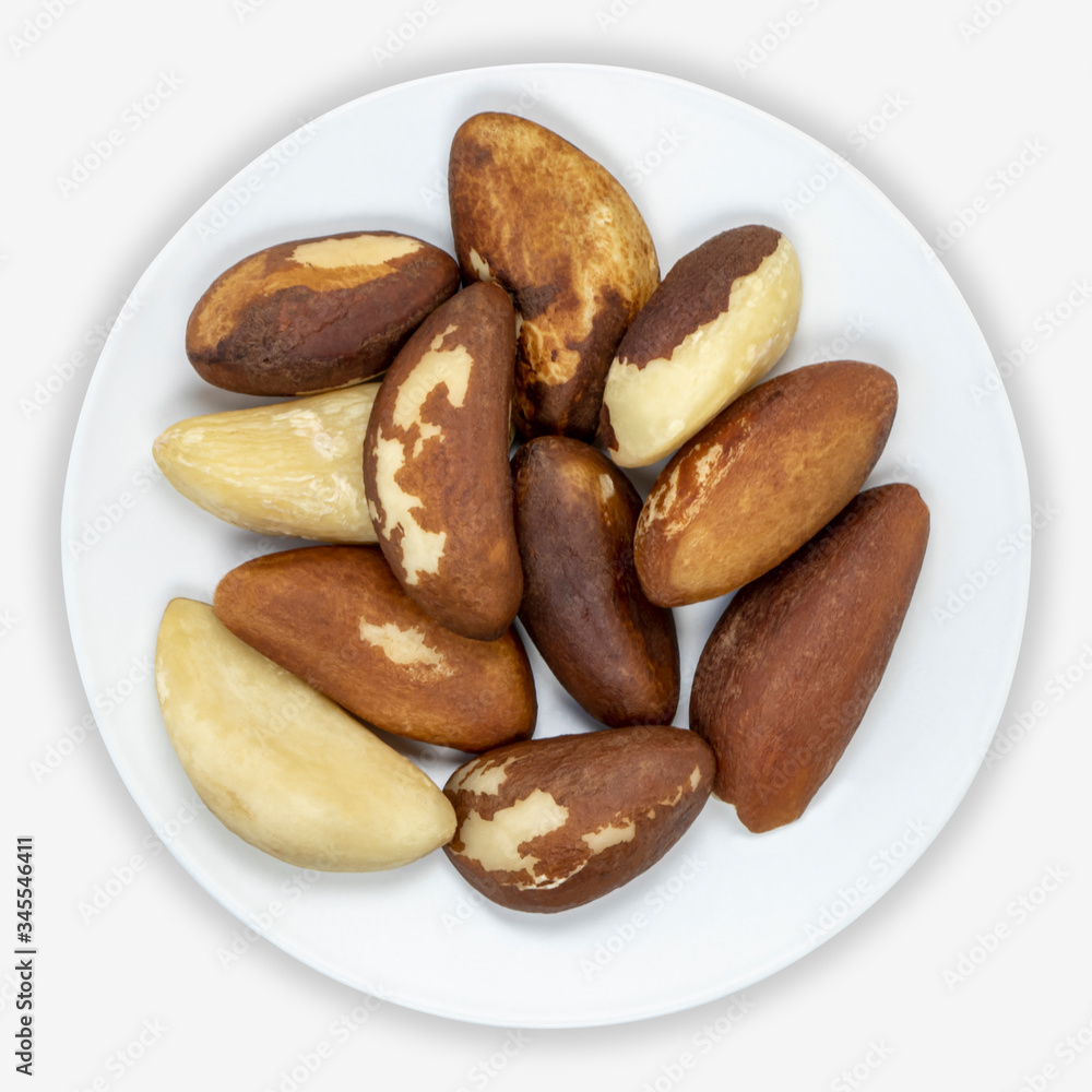 Brazil nuts (Bertholletia excelsa) on a white plate. Isolated background. View from above. Brazil nuts (Bertholletia excelsa) on a white plate. Isolated background. View from above.