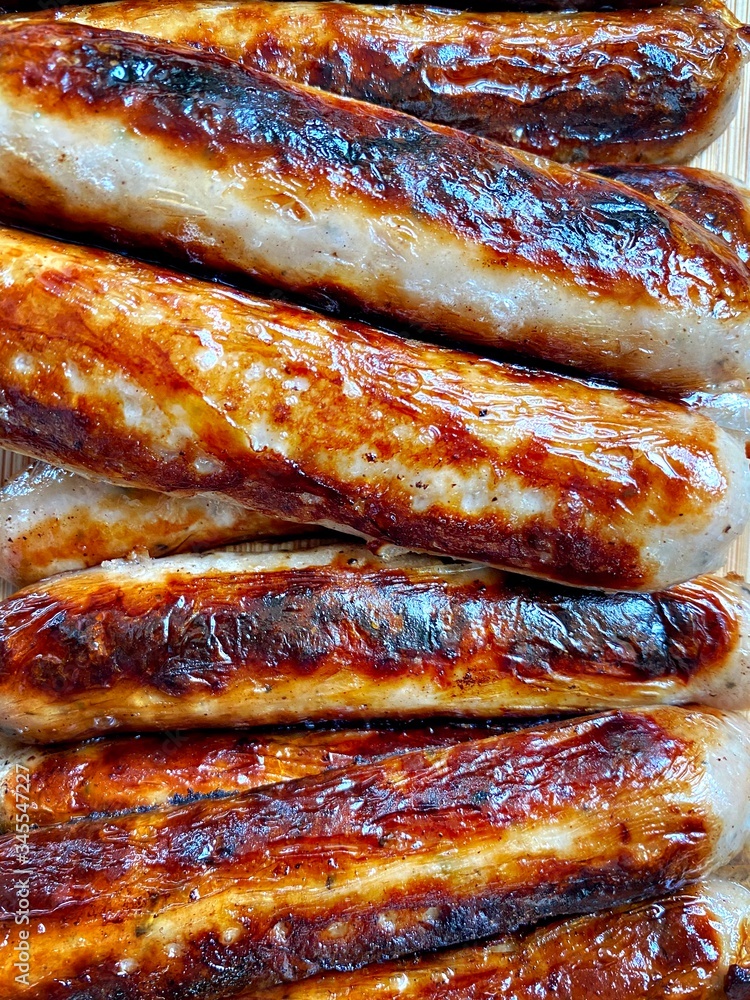 A closeup view of freshly prepared British Cumberland pork sausages. Filling the frame with cooked meat. Fried breakfast preparation.