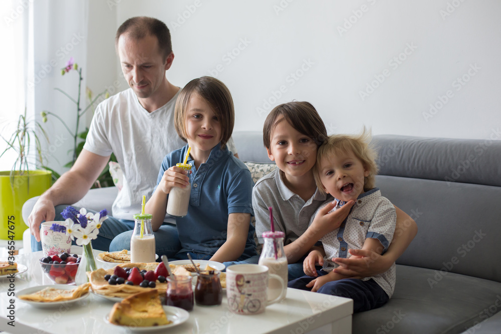 Happy family, having pancakes for breakfast, eating in living room, talking and lauging Happy family, having pancakes for breakfast, eating in living room, talking and lauging