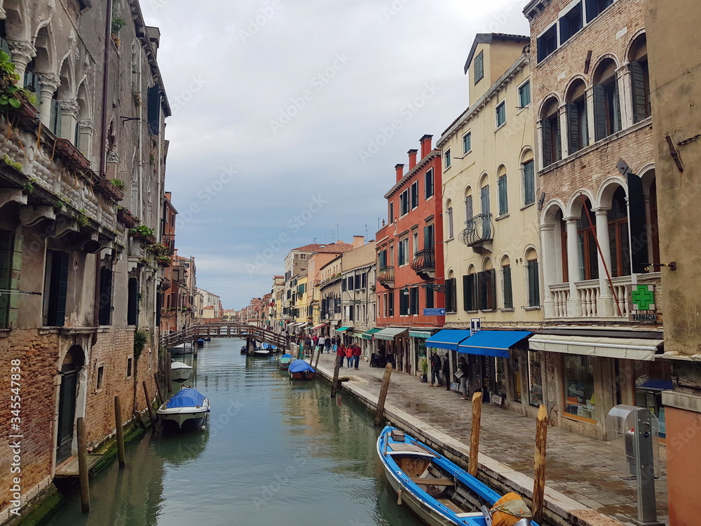 Venetian canal with boats and old houses on its banks