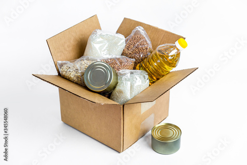 Food in cardboard donation box, isolated on white background. Anti-crisis stock of essential goods for period of quarantine isolation. Food delivery, coronavirus. The shortage of food. photo