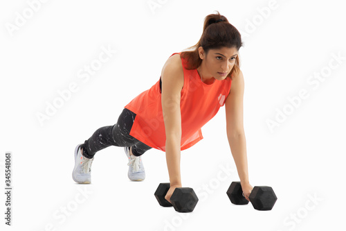 Woman doing push ups with dumbbells on a white background. 