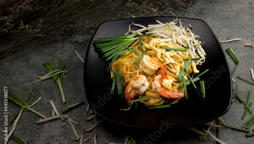 Thai fried noodles with prawns ( Pud Thai ) in black dish on table  photo