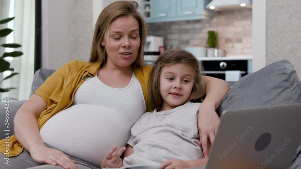 30s Cute Sweet Mother and Little Preschooler Child Pleasantly Surprised Looking at Laptop. Pretty Pregnant Woman and Small Adorable Daughter Sitting and Talking on Couch Nice Video Chat Conversation 30s Cute Sweet Mother and Little Preschooler Child Pleasantly Surprised Looking at Laptop. Pretty Pregnant Woman and Small Adorable Daughter Sitting and Talking on Couch Nice Video Chat Conversation