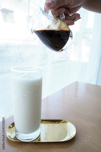 Pouring hot coffee into a glass of cold milk..Coffee is pouring into a glass with milkshake.