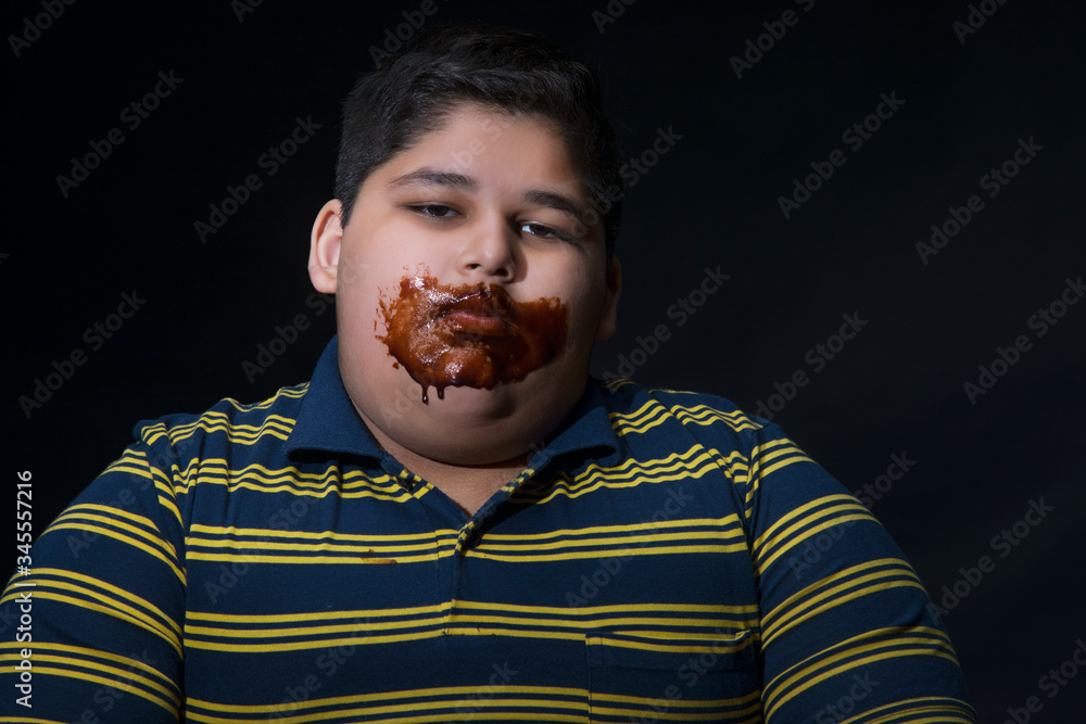 Portrait of a young boy with his mouth covered in chocolate. (Obesity) Portrait of a young boy with his mouth covered in chocolate. (Obesity)